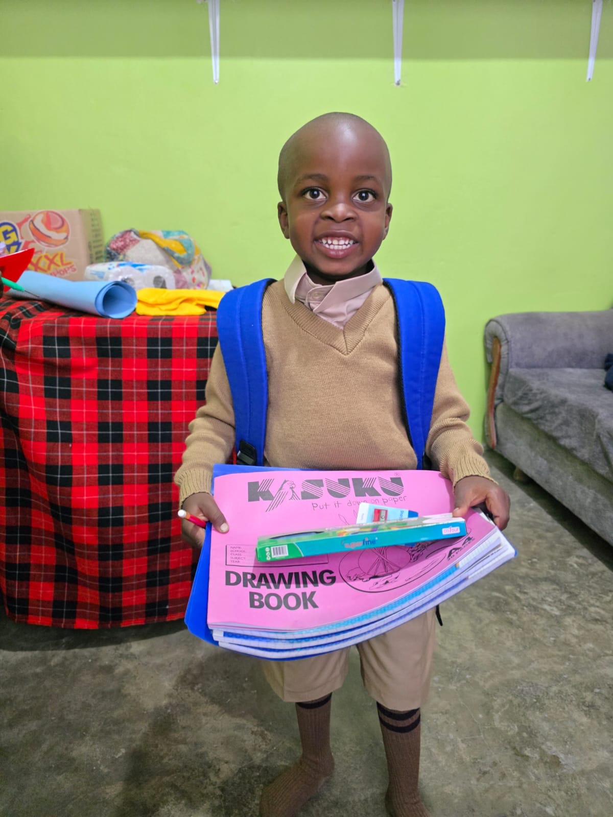 A young OnCourse-supported student holding new school supplies and wearing a backpack